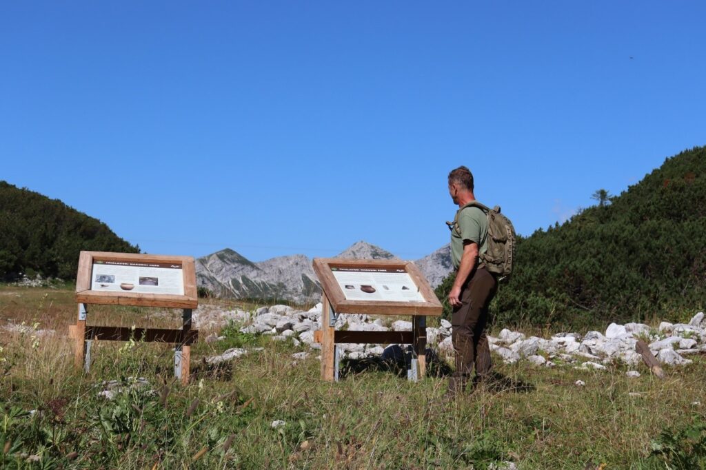 Moški stoji pred lesenimi tablami na poti na Vogel