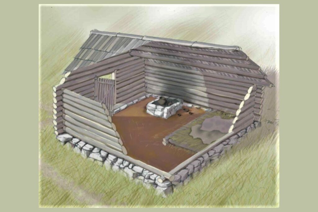 Rekonstrukcija lesenega naselja na Ajdovskem gradcu, ki prikazuje delno zgrajeno leseno kočo s kamnitimi temelji.